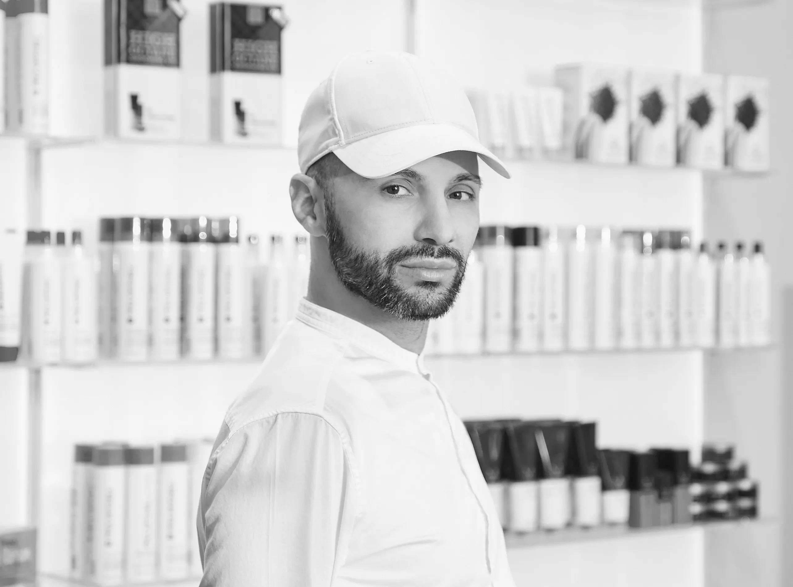Porträt eines Barbiers im Friseursalon vor Regalen mit Haarpflegeprodukten